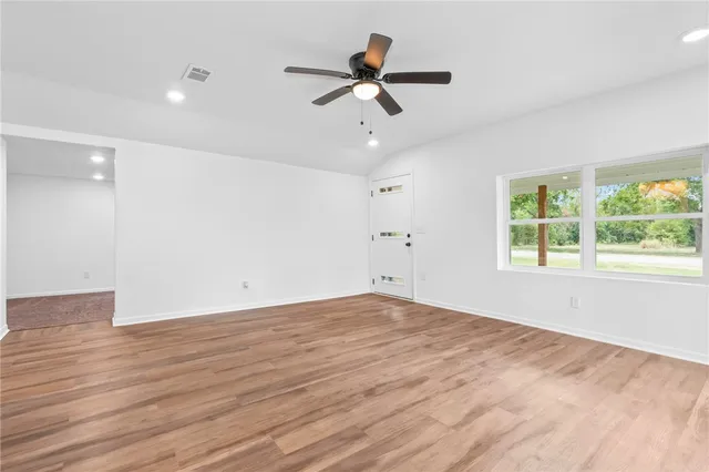 a view of an empty room with wooden floor and a window