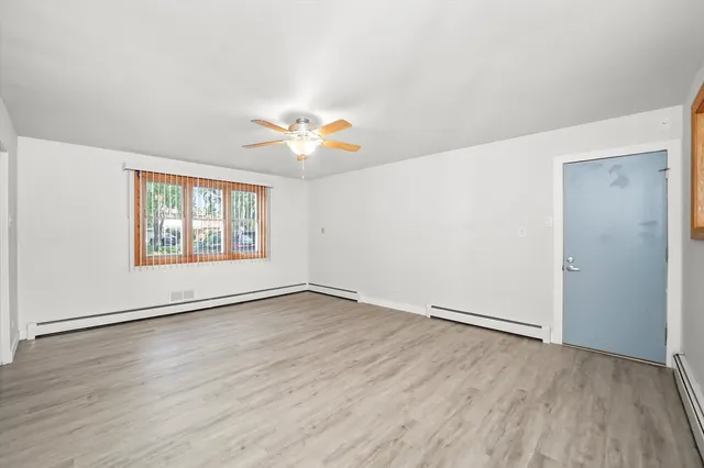 an empty room with wooden floor and window