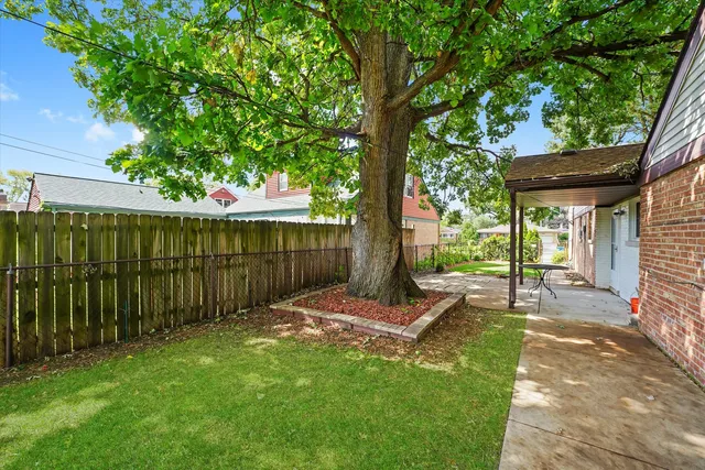 a view of a backyard with table and chairs and a large tree