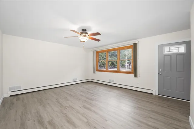 an empty room with wooden floor and window