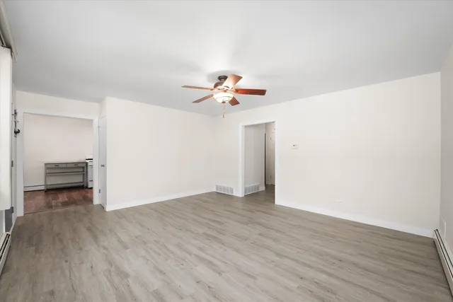 a view of a room with wooden floor and a ceiling fan