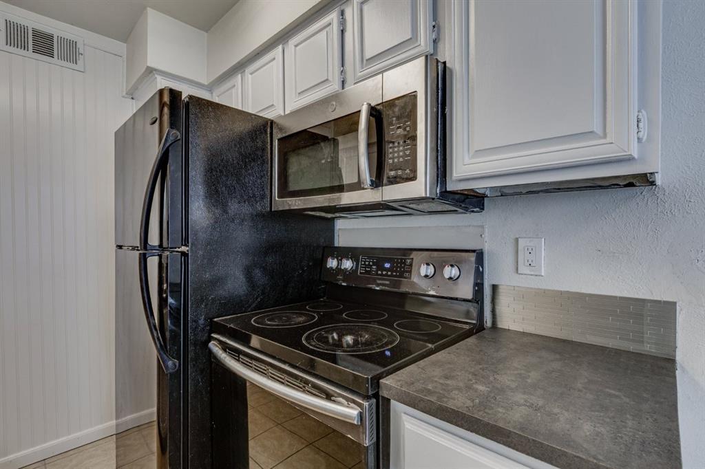 4606 Chaha Road, Unit 105 Garland, TX 75043 - Photo 12 of 26 Kitchen featuring appliances with stainless steel finishes, dark countertops, white cabinetry, and light tile patterned floors