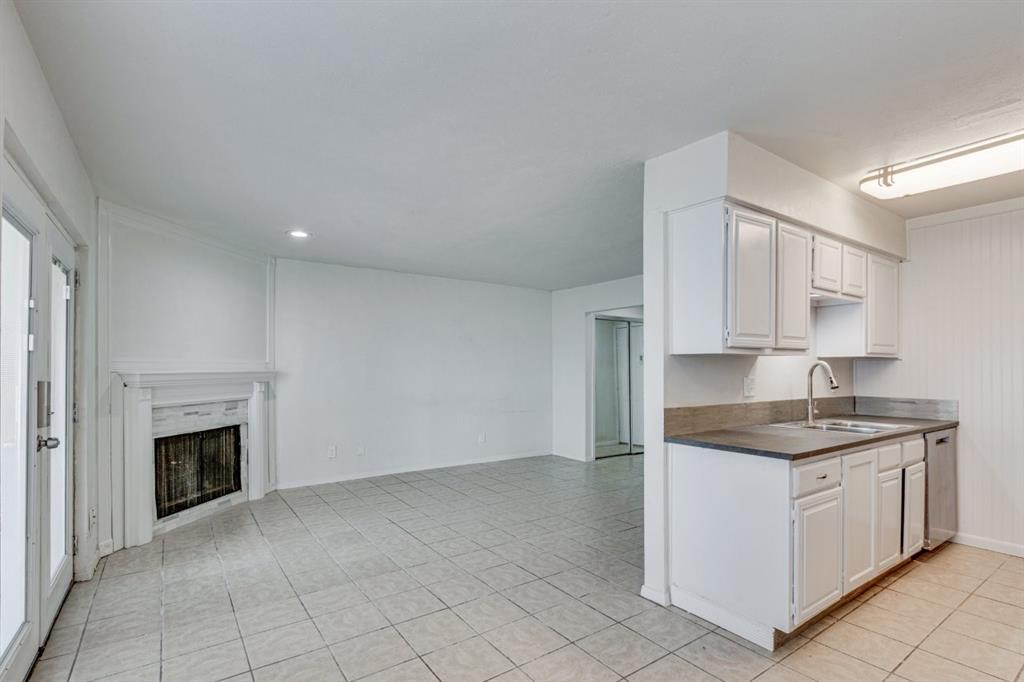 4606 Chaha Road, Unit 105 Garland, TX 75043 - Photo 15 of 26 Kitchen with white cabinets, a fireplace, dark countertops, and light tile patterned floors