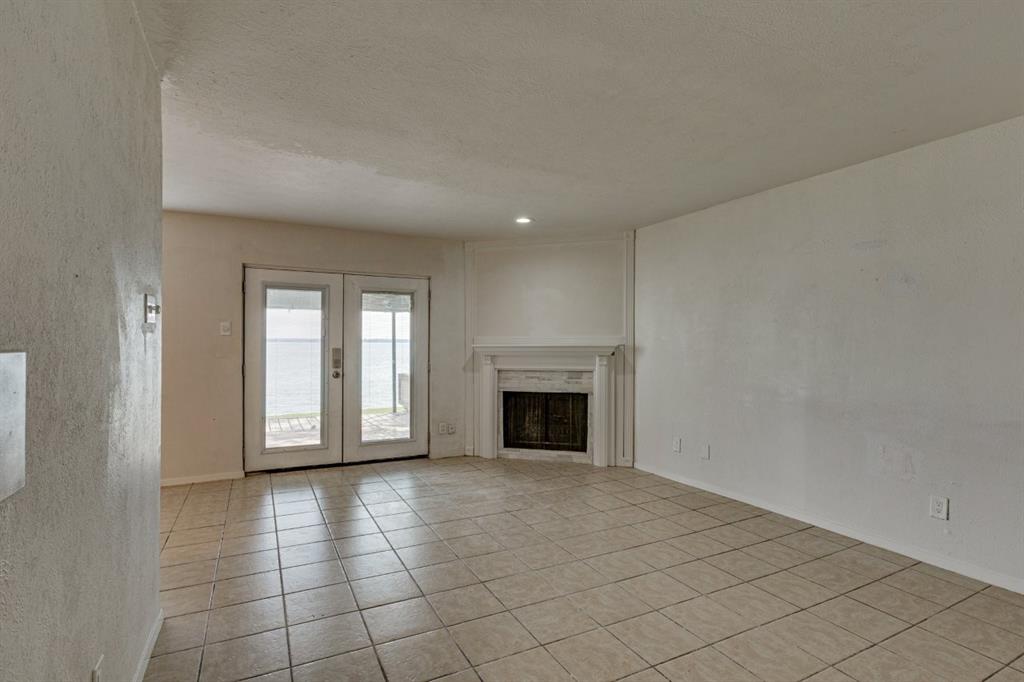4606 Chaha Road, Unit 105 Garland, TX 75043 - Photo 8 of 26 Unfurnished living room with light tile patterned floors, french doors, a fireplace, and a textured ceiling