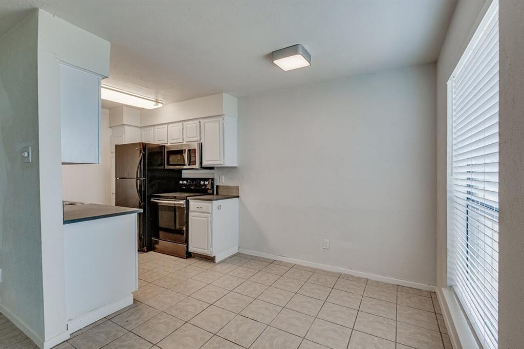 4606 Chaha Road, Unit 105 Garland, TX 75043 - Photo 9 of 26 Kitchen featuring dark countertops, stainless steel appliances, white cabinetry, and light tile patterned floors
