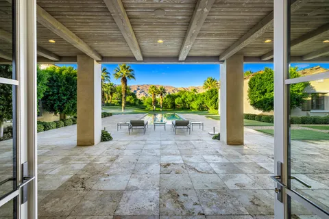 a view of a patio with table and chairs potted plants with floor to ceiling window