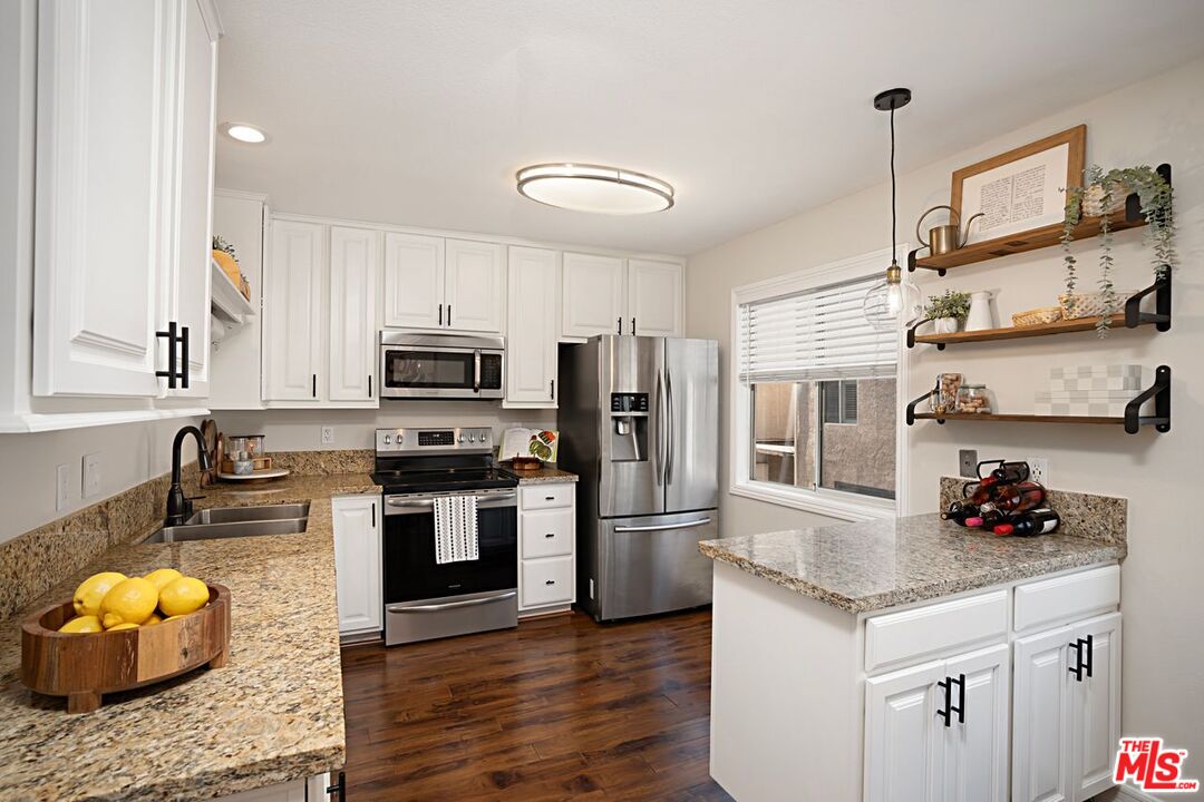 7774 Vía Rosa Maria Burbank, CA 91504 - Photo 7 of 22 a kitchen with granite countertop kitchen island stainless steel appliances a stove refrigerator sink and cabinets