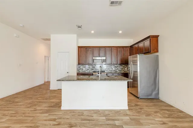 a kitchen with stainless steel appliances granite countertop a refrigerator and a stove
