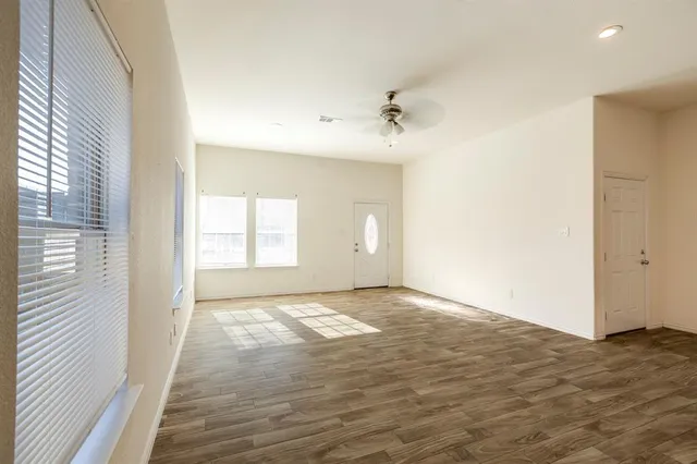a view of an empty room with window and wooden floor