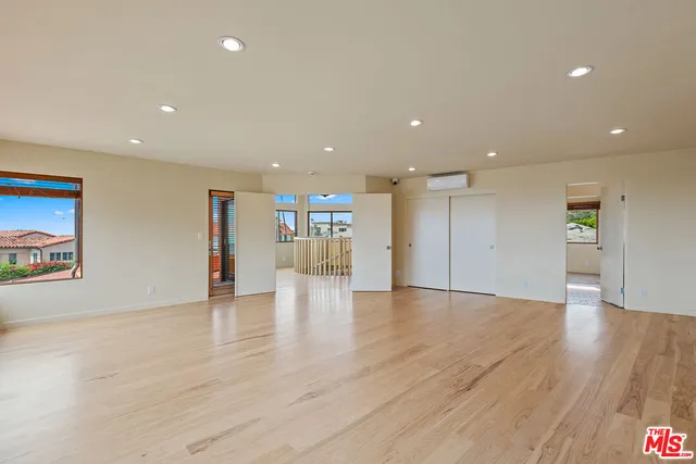 a view of an empty room with wooden floor and window