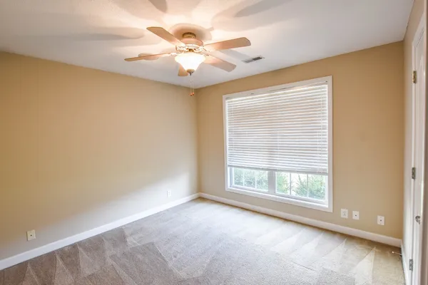 an empty room with windows and chandelier fan