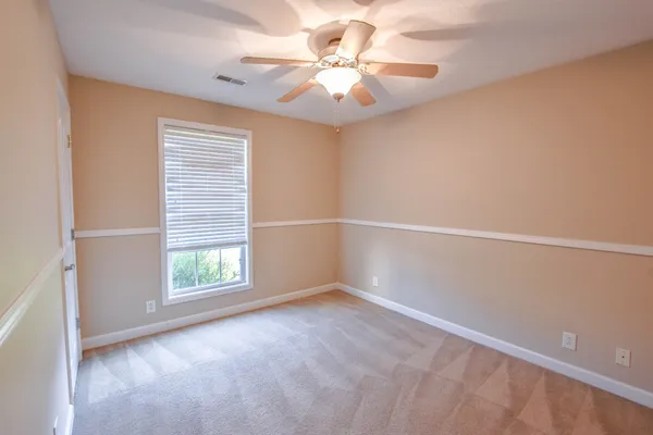 an empty room with windows and fan