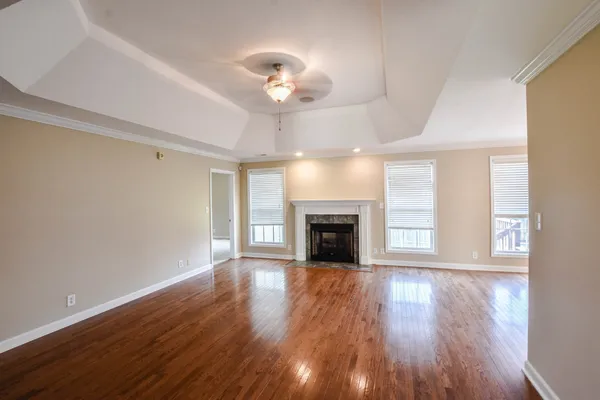 a view of an empty room with wooden floor fireplace and a window