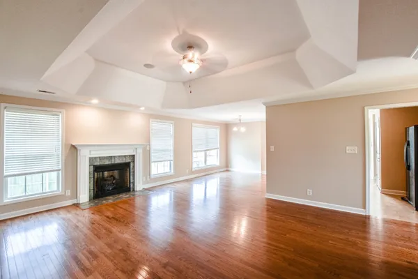 an empty room with wooden floor fireplace and windows