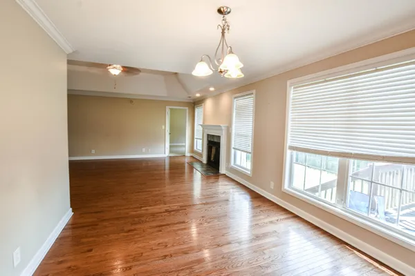 a view of a room with wooden floor a ceiling fan and windows