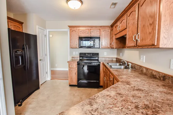 a kitchen with stainless steel appliances granite countertop a refrigerator a stove top oven a sink and dishwasher