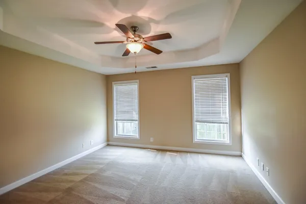 an empty room with windows and fan