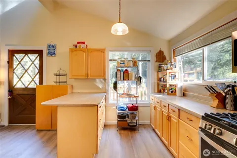 a kitchen that has a sink and a stove with wooden floor