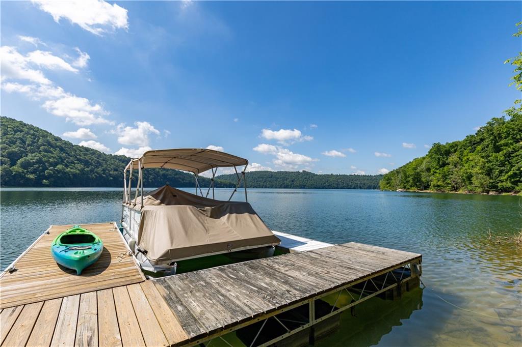 2675 Lakeview Road Confluence, PA 15424 - Photo 23 of 25 a view of a roof deck with table and chairs under an umbrella with wooden floor and lake view