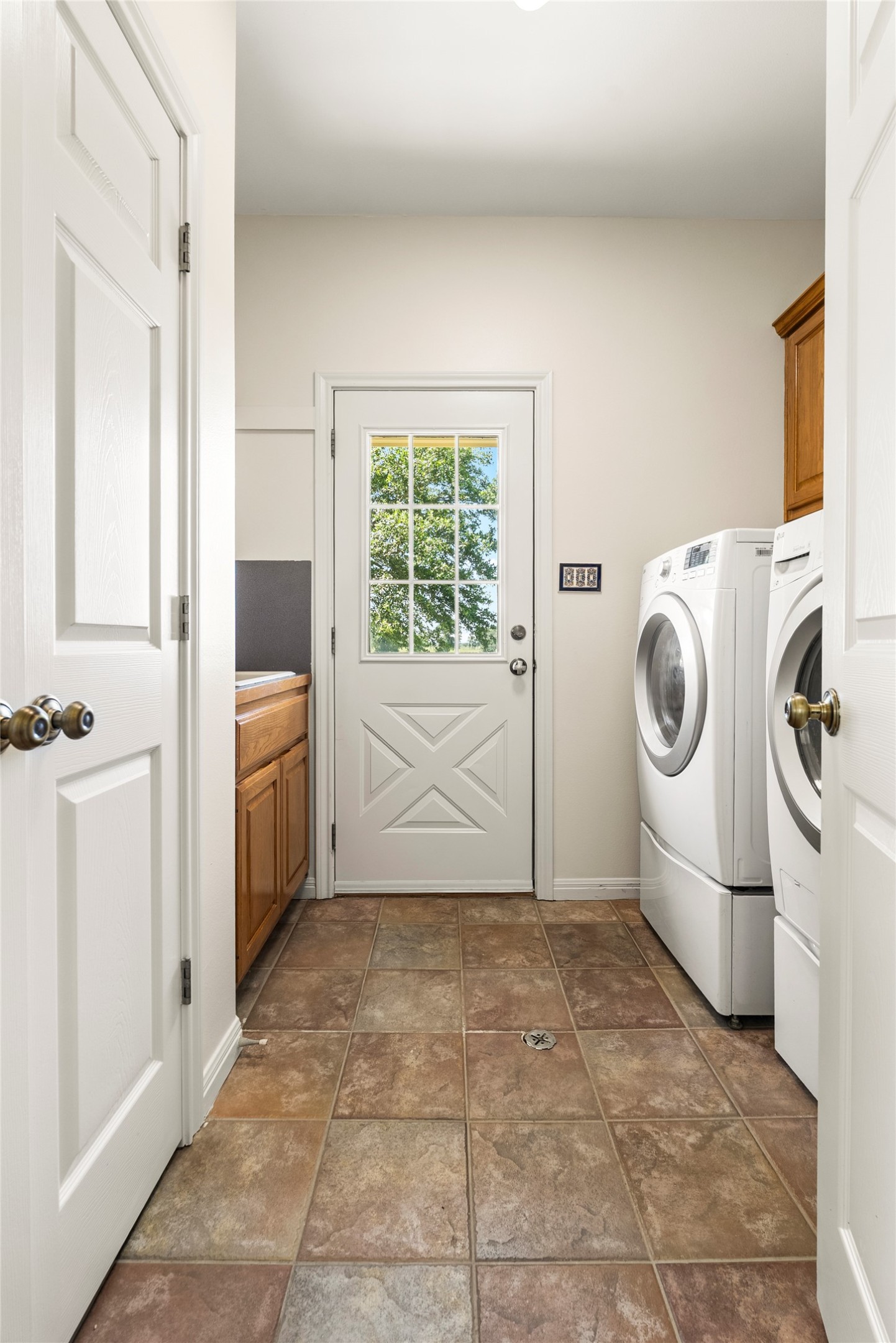 928 Upper Elgin River Road Elgin, TX 78621 - Photo 30 of 40 Utility room with multi-toned tile flooring and a white door featuring a window with grid detailing.