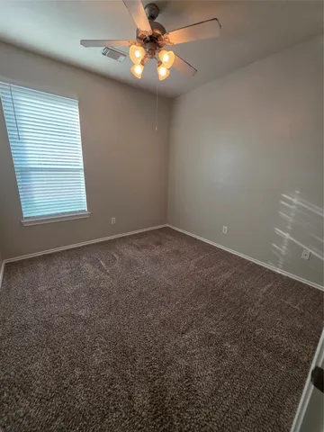 an empty room with a window and ceiling fan