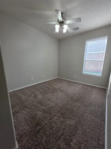 an empty room with windows and fan