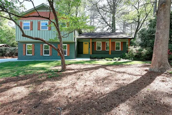 a front view of a house with a yard and trees