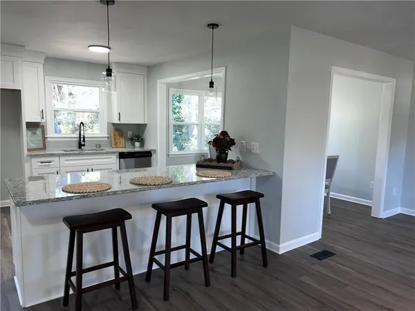 a kitchen with granite countertop white cabinets and a window