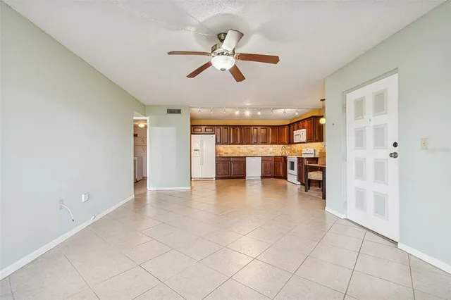 a view of a livingroom with a ceiling fan & kitchen space