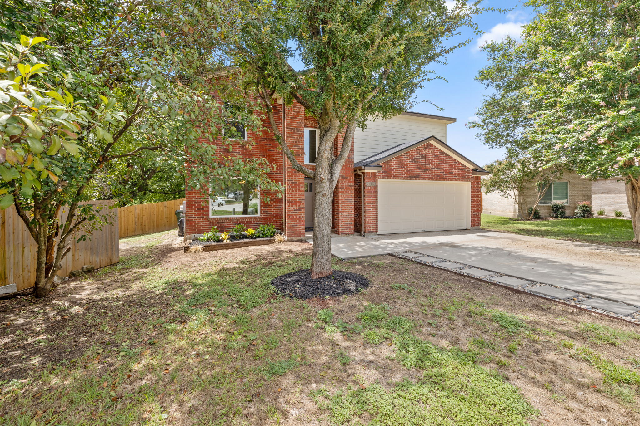 909 Rocking Spur Cove Pflugerville, TX 78660 - Photo 2 of 33 Mature trees frame this brick-clad residence, featuring a two-car garage and a landscaped entry.