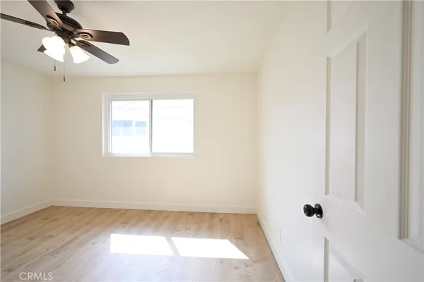 a view of a room with wooden floor fan and windows