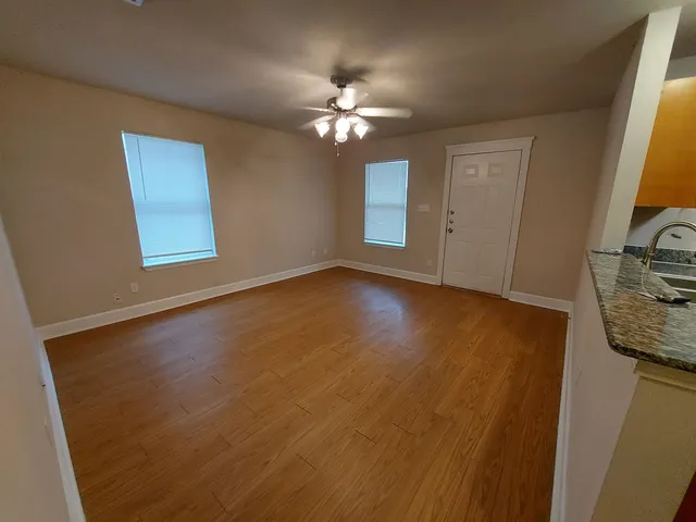 a view of a livingroom with a chandelier fan and wooden floor