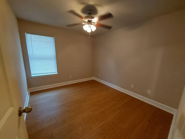 an empty room with windows and fan