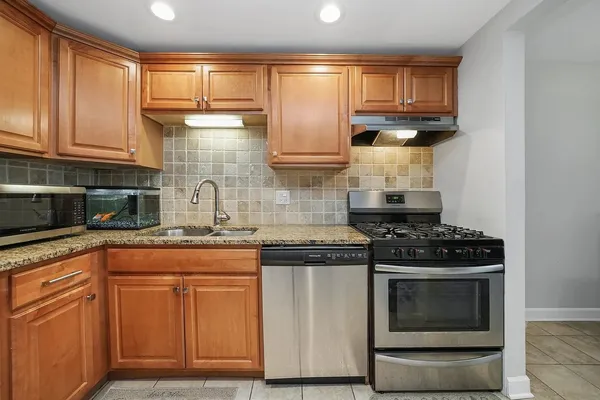 a kitchen with granite countertop wooden cabinets and a stove top oven