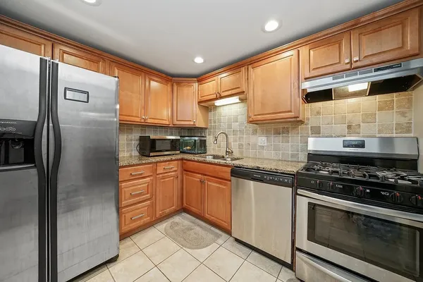 a kitchen with stainless steel appliances granite countertop a refrigerator a stove and a sink