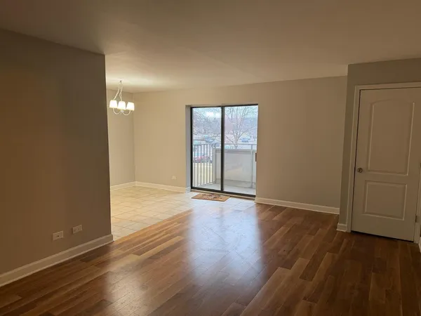an empty room with wooden floor and windows with curtains