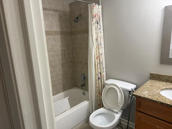 a bathroom with a granite countertop toilet and a shower