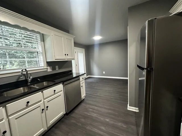 a kitchen with granite countertop a refrigerator a sink and cabinets
