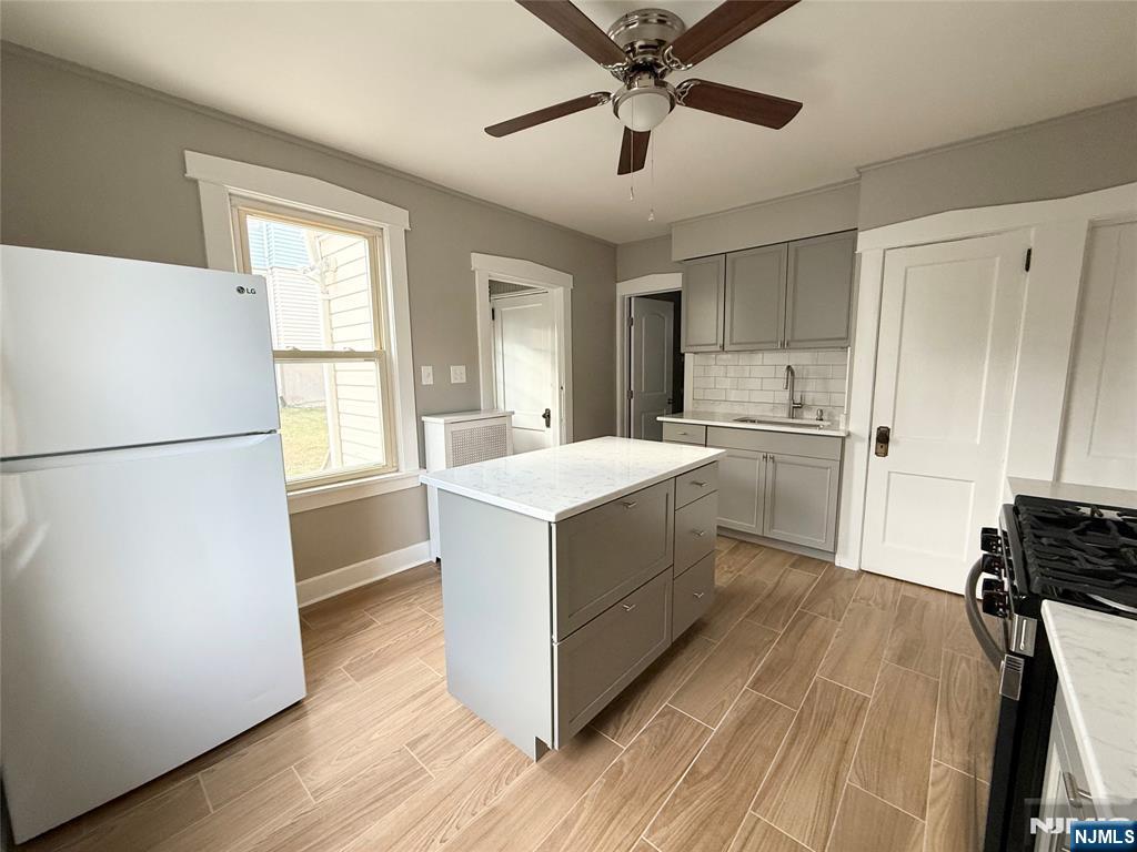 140 Westervelt Avenue, Unit 1 Hawthorne, NJ 07506 - Photo 3 of 20 a kitchen with a refrigerator and white cabinets