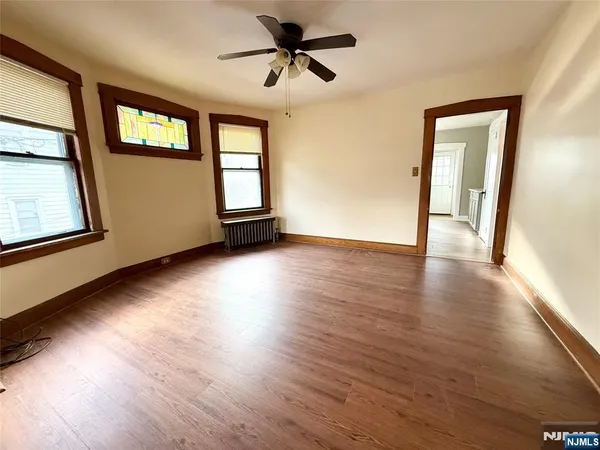 a view of an empty room with wooden floor and a window