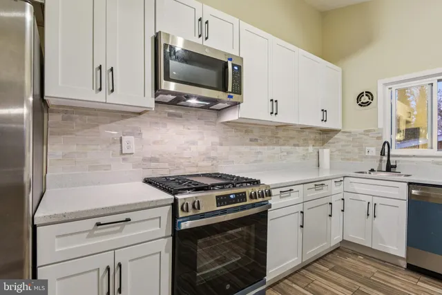 a kitchen with cabinets stainless steel appliances and wooden floor