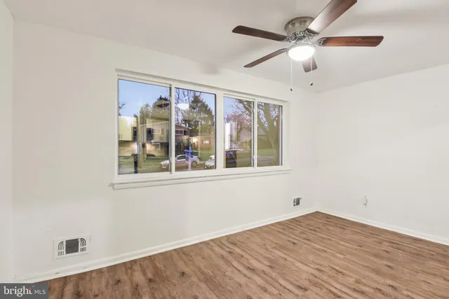 an empty room with wooden floor fan and windows