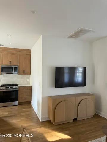 a view of kitchen with stainless steel appliances wooden floor and stove