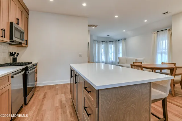 a kitchen with kitchen island a stove a table and chairs in it