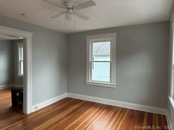 an empty room with wooden floor closet and windows