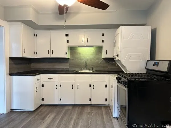 a kitchen with stainless steel appliances granite countertop a stove a sink and white cabinets