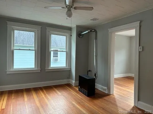 an empty room with wooden floor closet and windows