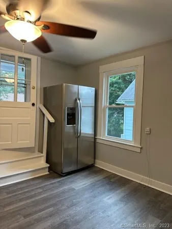 an empty room with wooden floor cabinet and windows