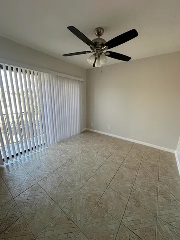 an empty room with a ceiling fan and window