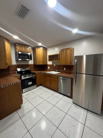 a kitchen with granite countertop a refrigerator and a stove top oven